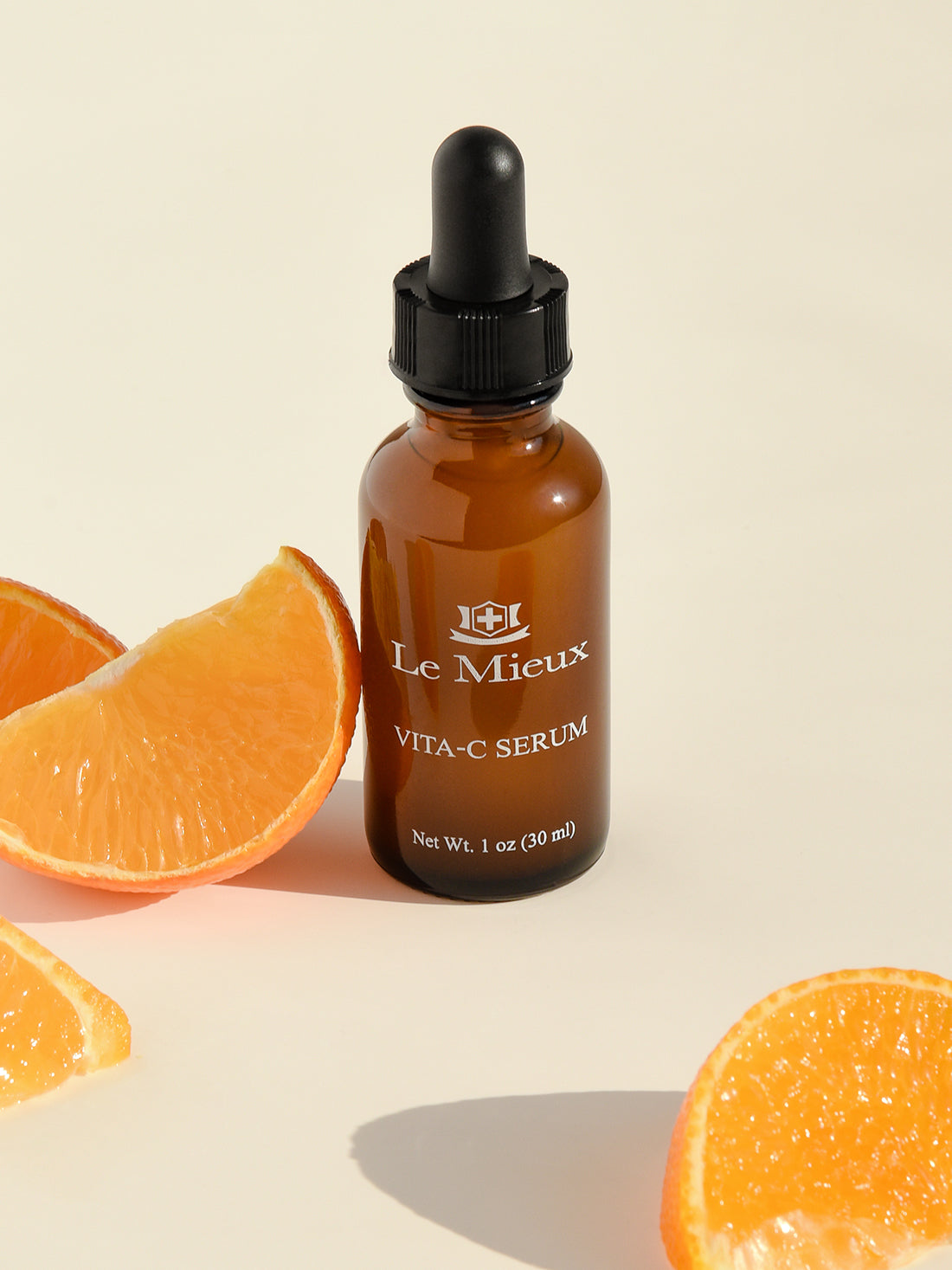 Vita-C Serum next to orange slices on a cream background