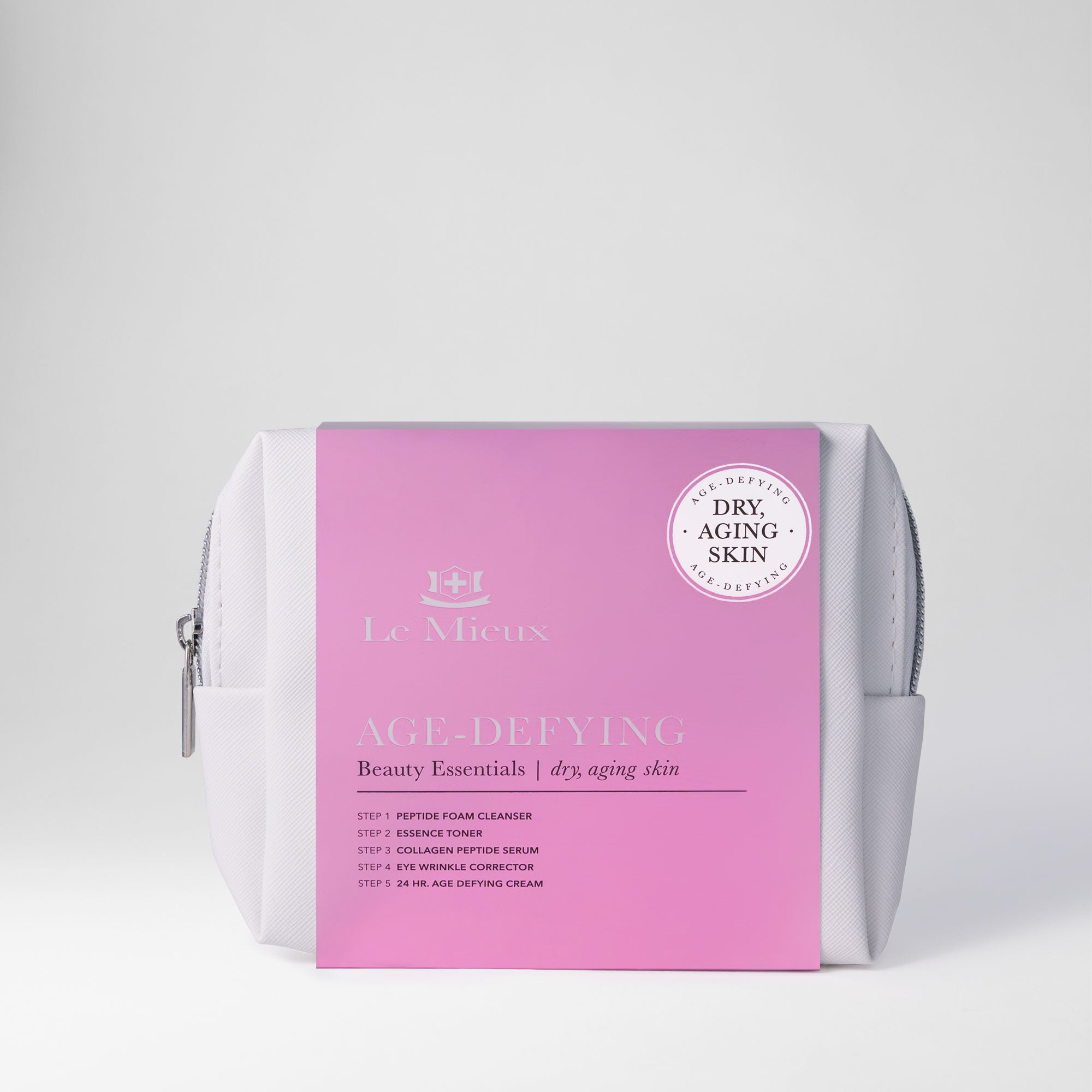 White bag with silver zipper and pink sleeve that says Age-Defying Beauty Essentials with Le Mieux logo in front of a light gray background.