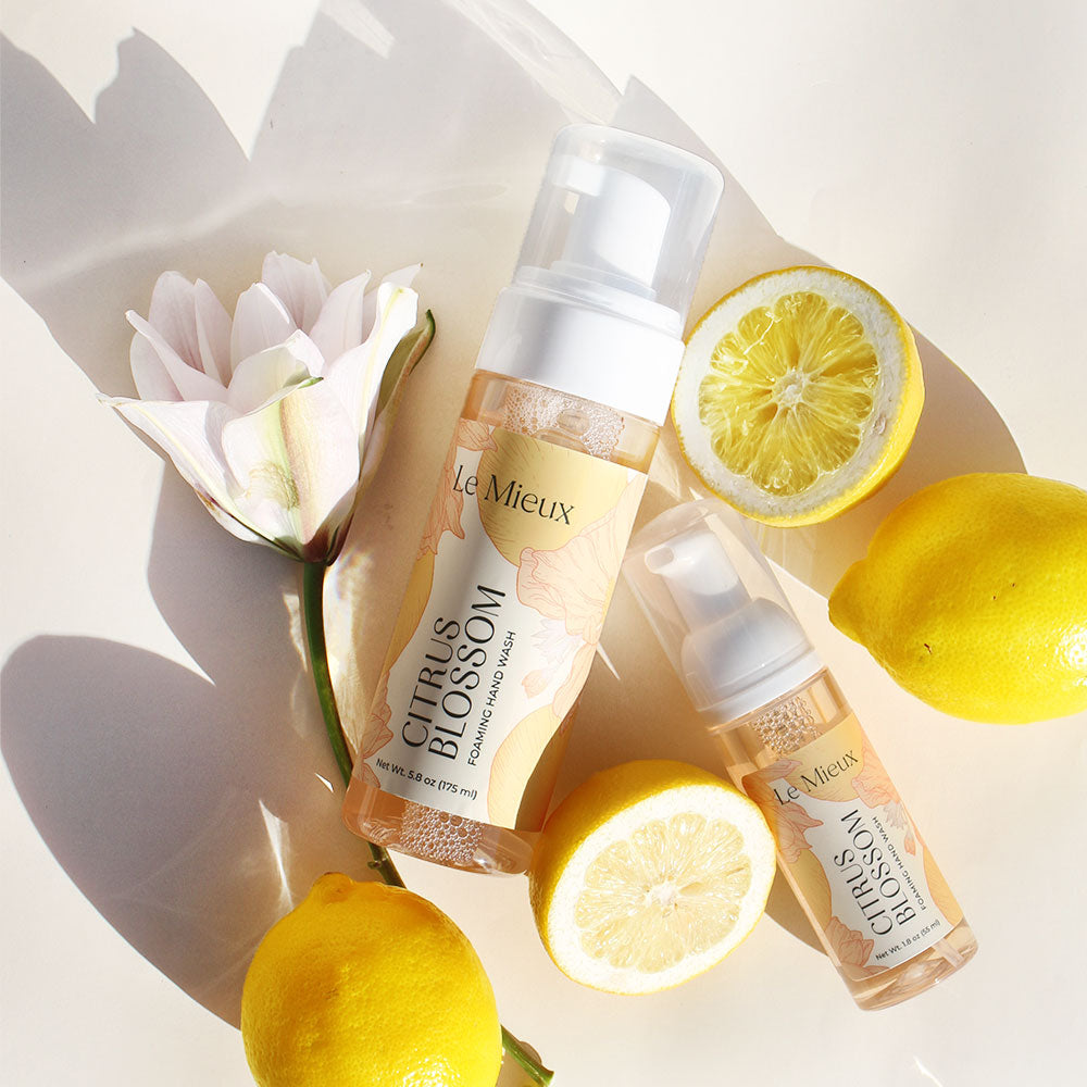 Citrus Blossom Foaming Hand Wash (5.8 oz and 1.8 oz) on a light cream background, surrounded by lemons and a single flower