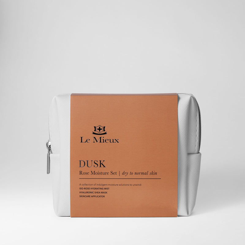 White bag with silver zipper and light brown sleeve that says Dusk Rose Moisture Set with Le Mieux logo in front of a light gray background.