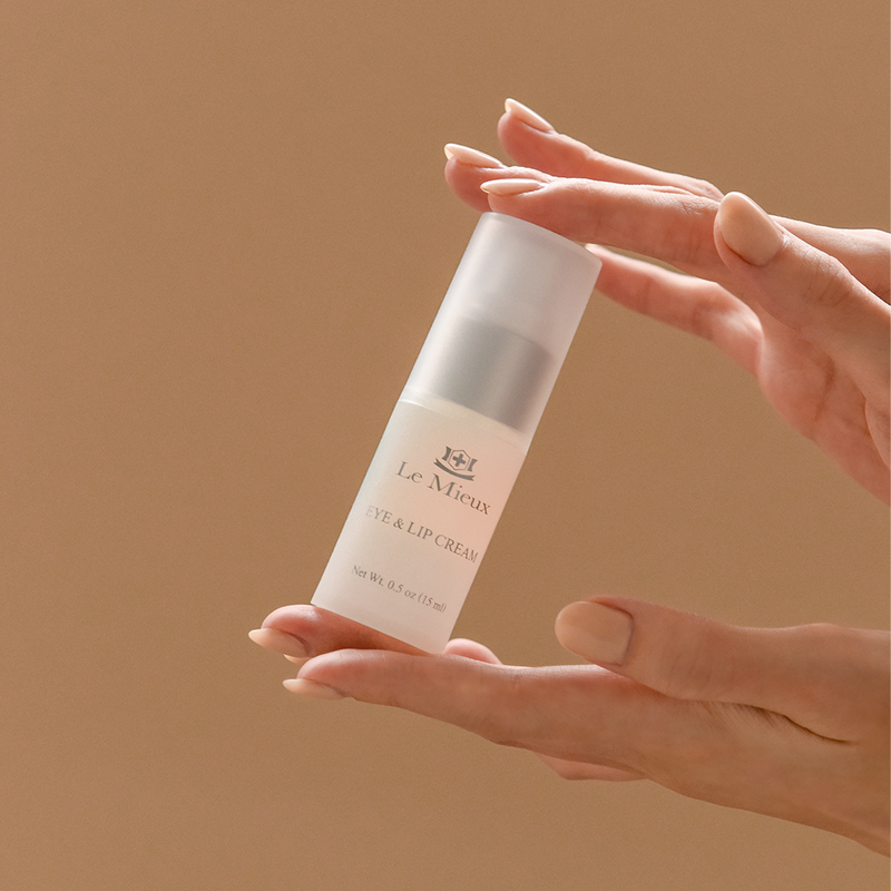 Eye & Lip Cream product being held between two hands in front of a light brown background