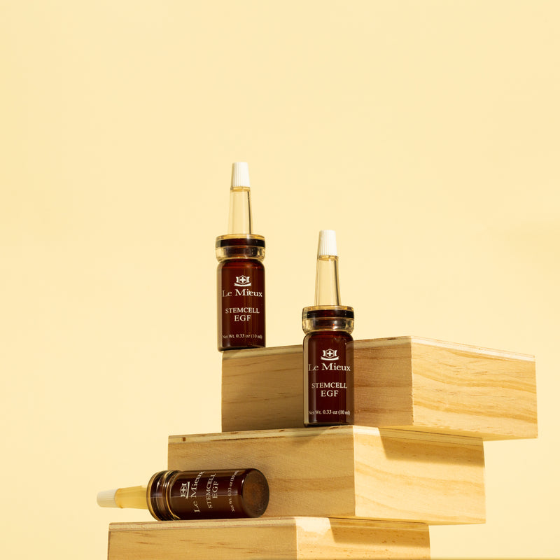 three amber bottles of Stemcell EGF on a stack of three wooden stands in front of a light yellow background