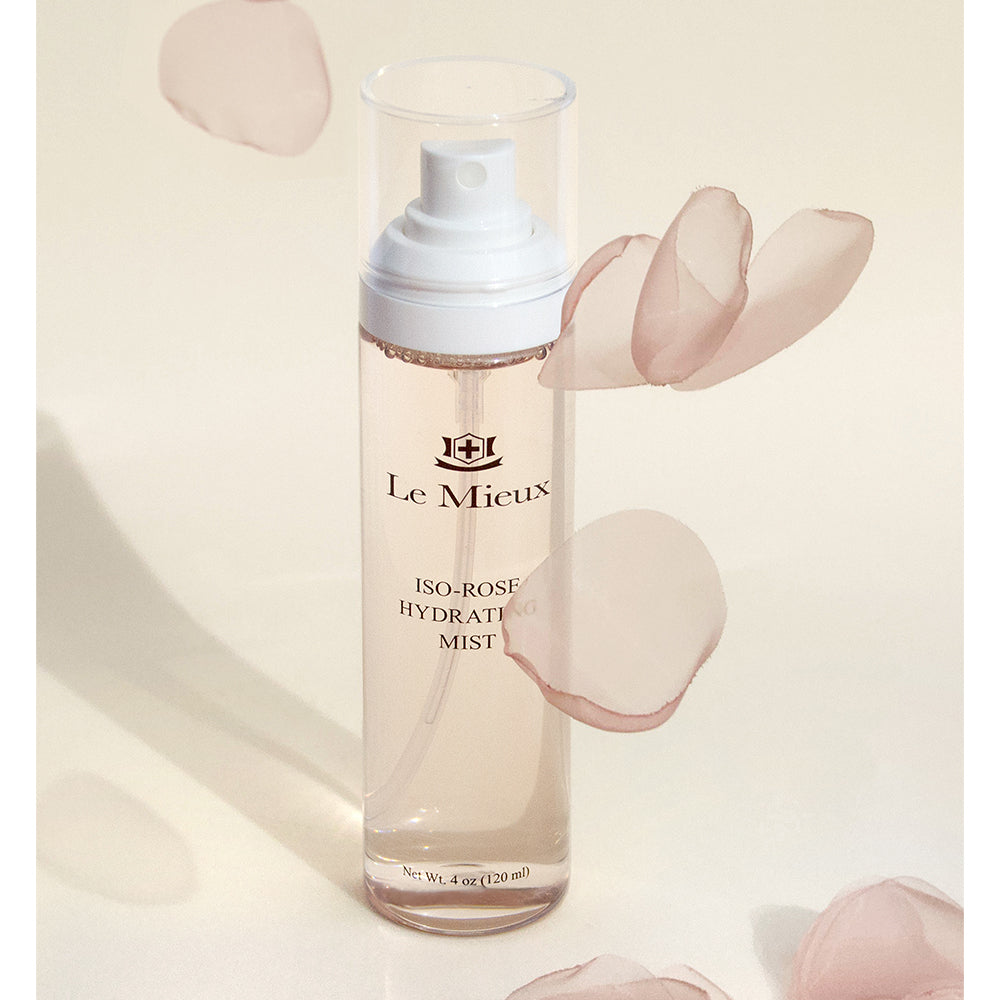 Iso-Rose Hydrating Mist with light pink rose petals falling around it in front of a light yellow background